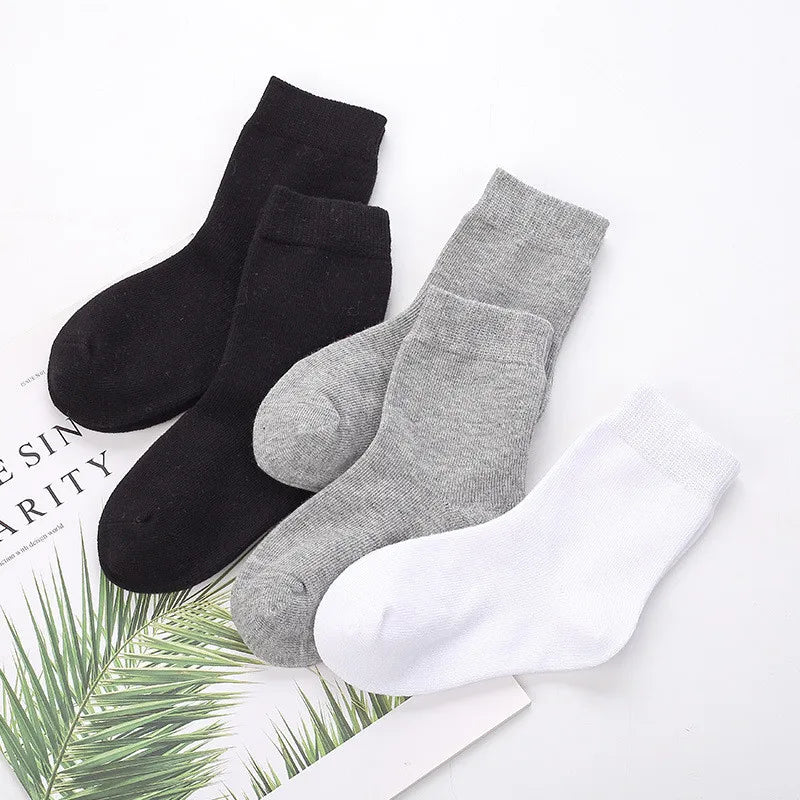 Three pairs of socks in black, gray, and white on a white background with green leaves.
