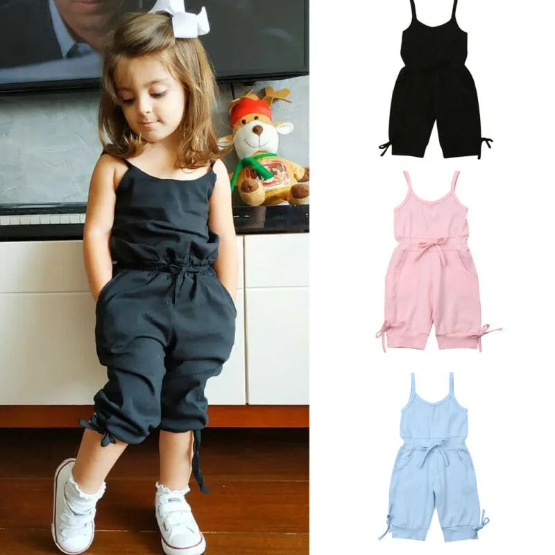 Child wearing a black romper with additional rompers in black, pink, and blue shown on the right.