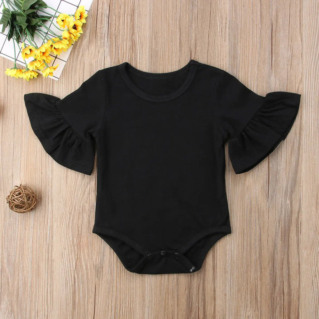Black baby romper with ruffled sleeves on a wooden surface