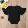 Black baby romper with ruffled sleeves on a wooden surface