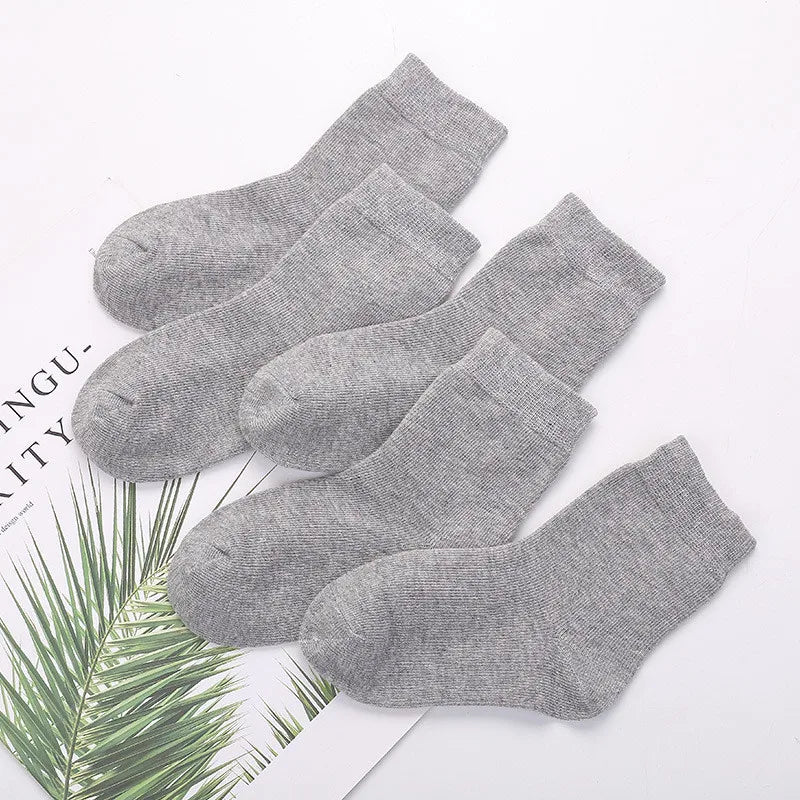 Set of gray socks on a white background with green leaves.
