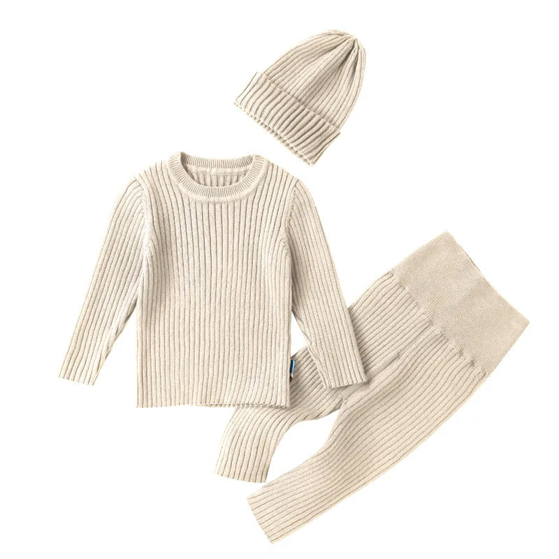 Beige knit sweater, pants, and beanie set on a white background