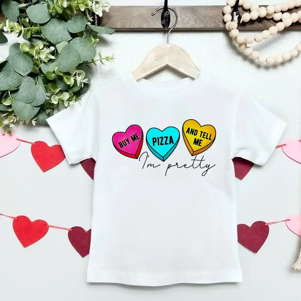 White t-shirt with colorful heart graphics and text on a white background with decorative elements.