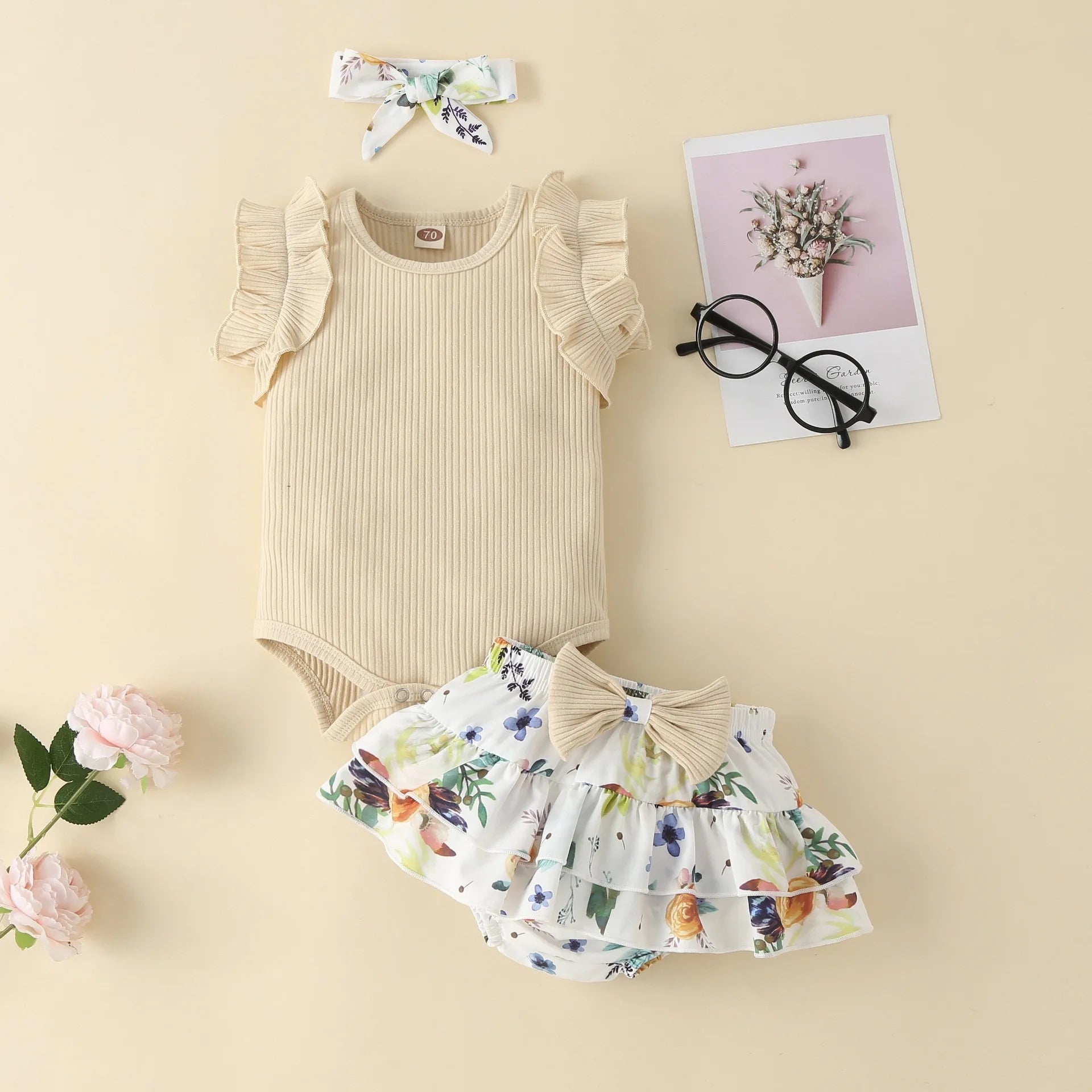 Baby outfit with beige romper and floral skirt on a beige background