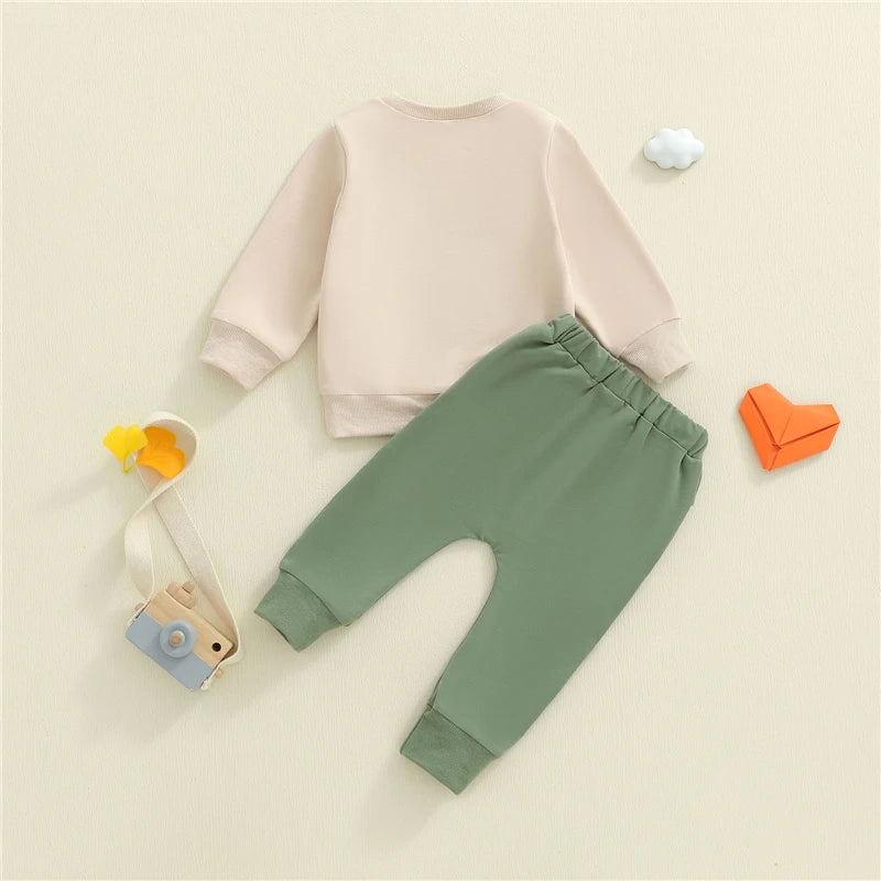 Baby outfit with pink top and green pants on a beige background