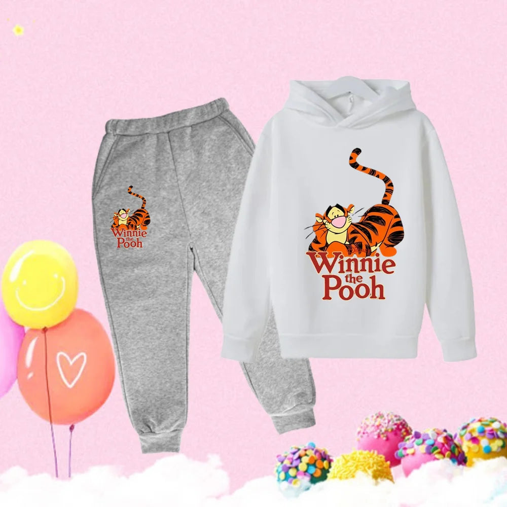 Winnie the Pooh-themed hoodie and pants set on a pink background with balloons and candy.