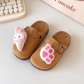 Brown slippers with pink ice cream and paw print design on a light surface.
