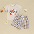 Children's outfit with 'Game Day' t-shirt and checkered shorts on a beige background