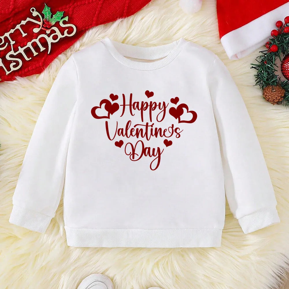 White sweatshirt with 'Happy Valentine's Day' text on a textured surface with Christmas decorations.