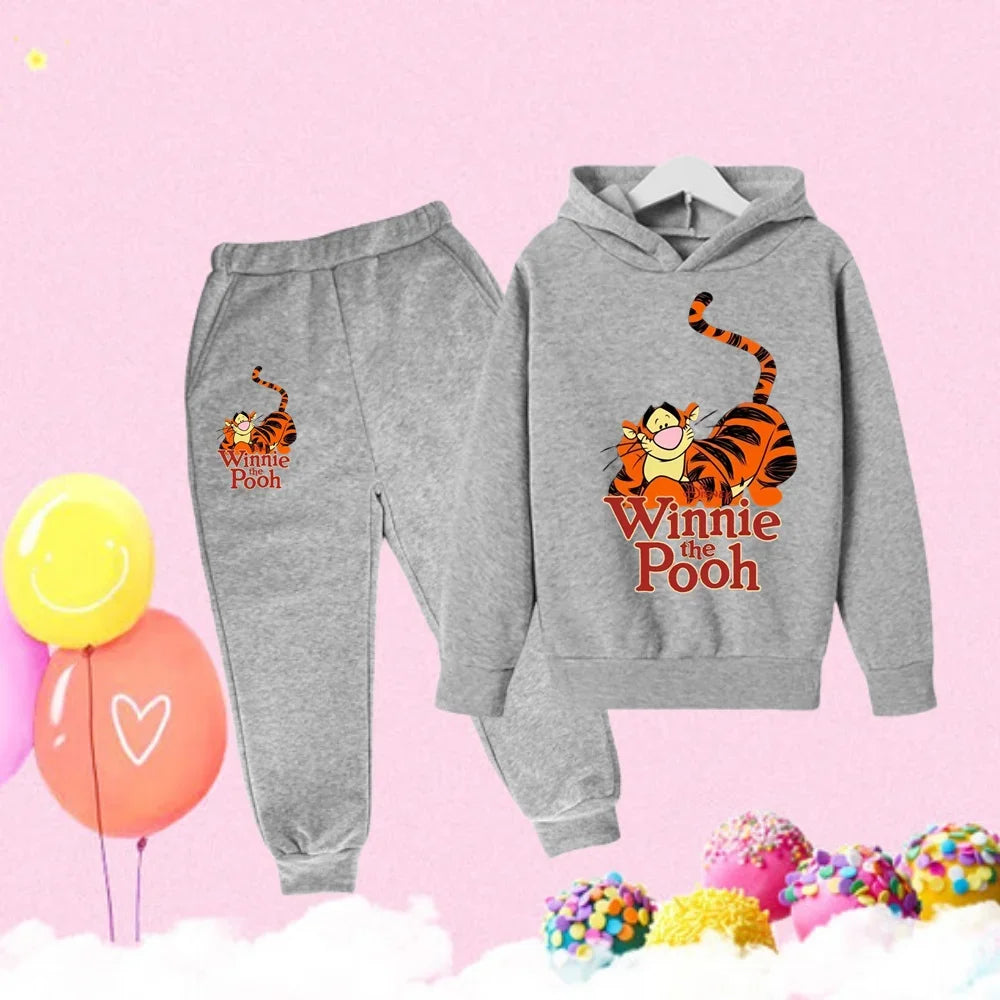 Gray 'Winnie the Pooh' hoodie and pants set on a pink background with balloons and candy.