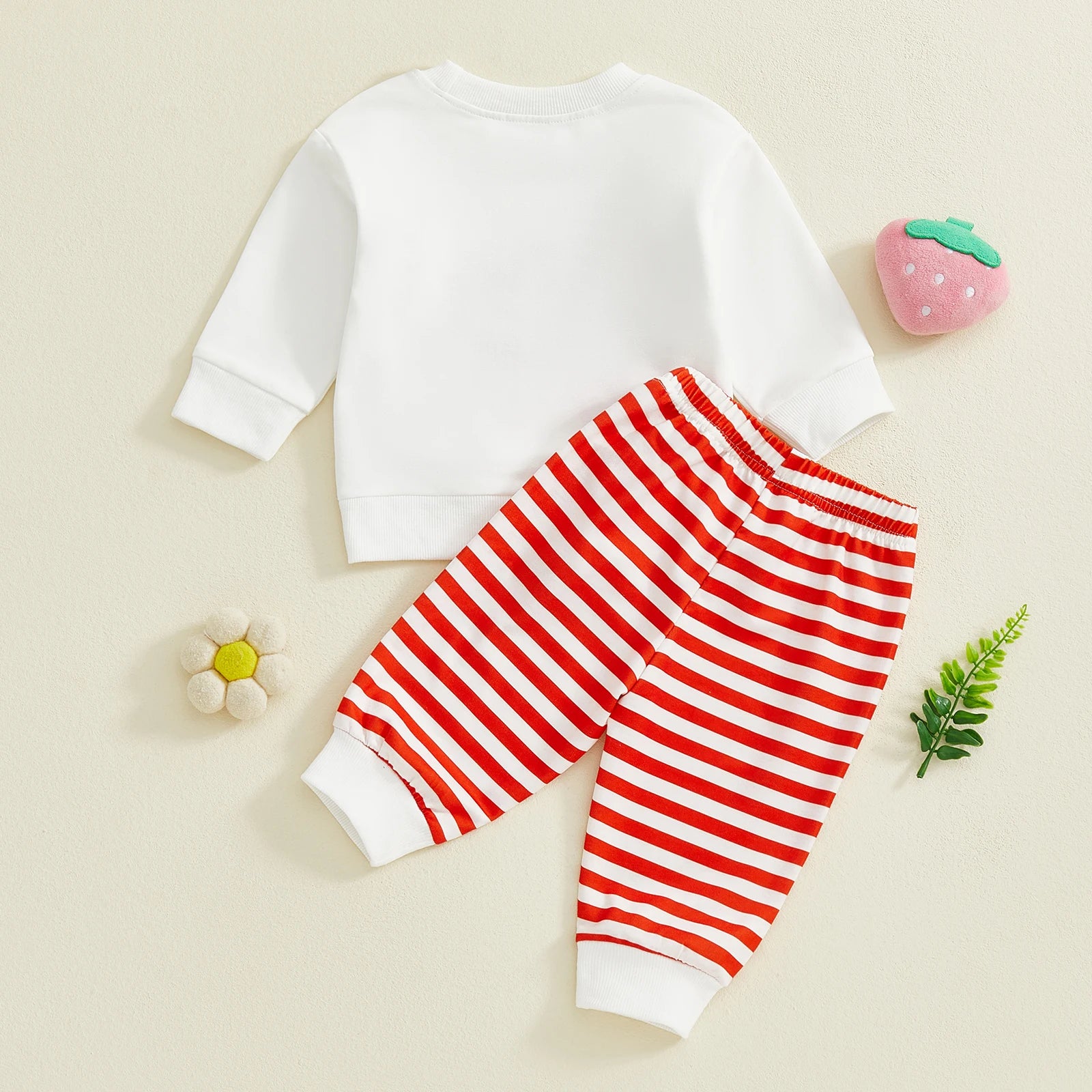 White long-sleeve top and red and white striped pants on a beige background