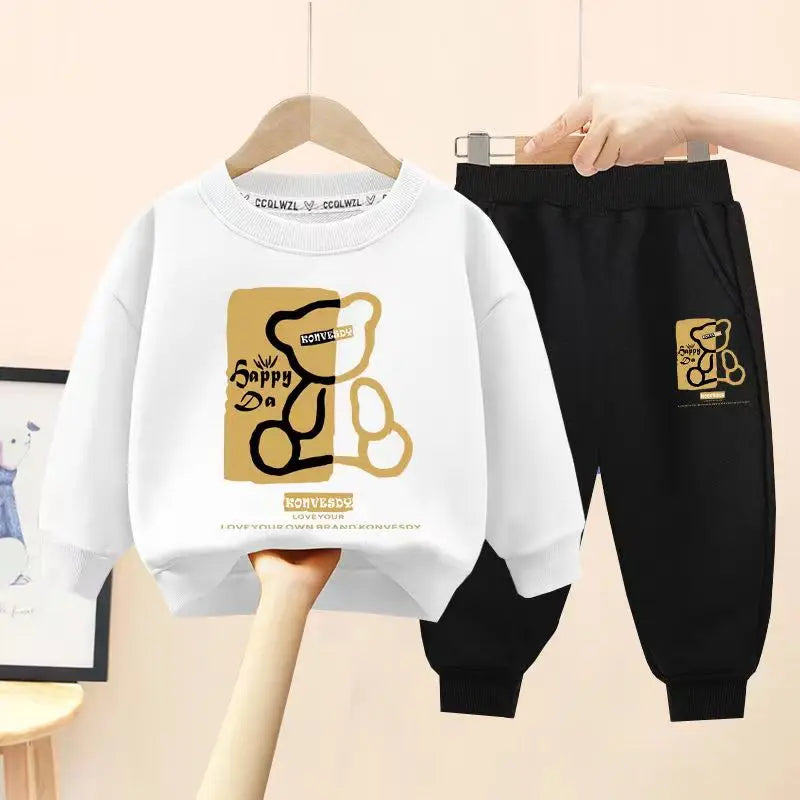 White sweatshirt and black pants with a gold bear logo on a beige background