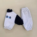 Gray baby pants with black cuffs and blue text on a beige background