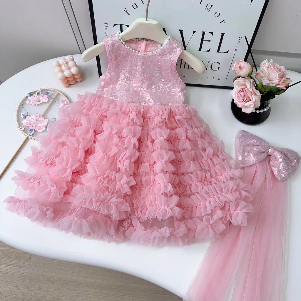 Pink children's dress with ruffles on a white surface