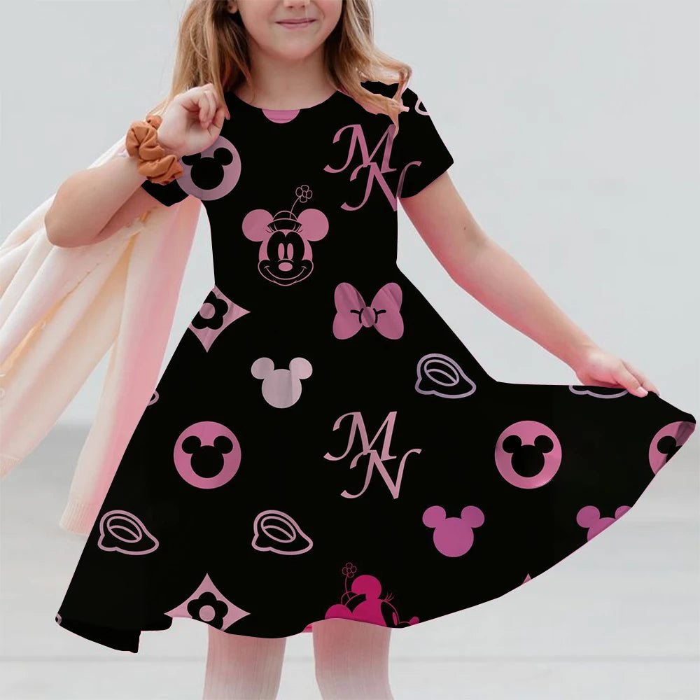 Child wearing a black dress with pink Minnie Mouse patterns on a plain background