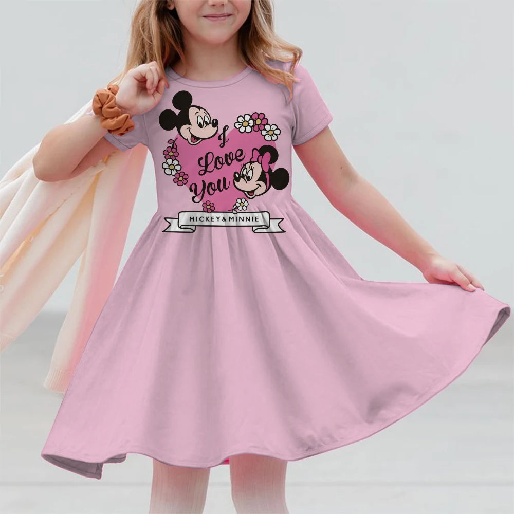 Child wearing a pink dress with Minnie Mouse design on a plain background