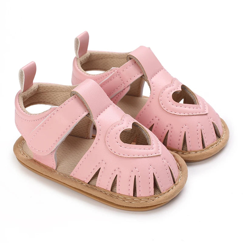 Pink baby sandals with heart designs on a white background