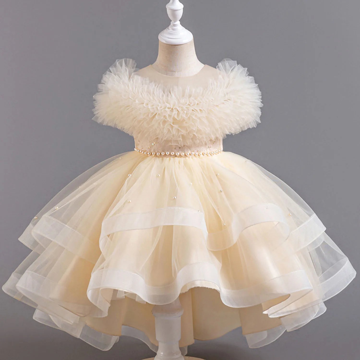Beige children's dress on a mannequin against a gray background