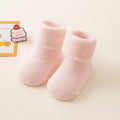 Pair of pink baby socks on a light beige background