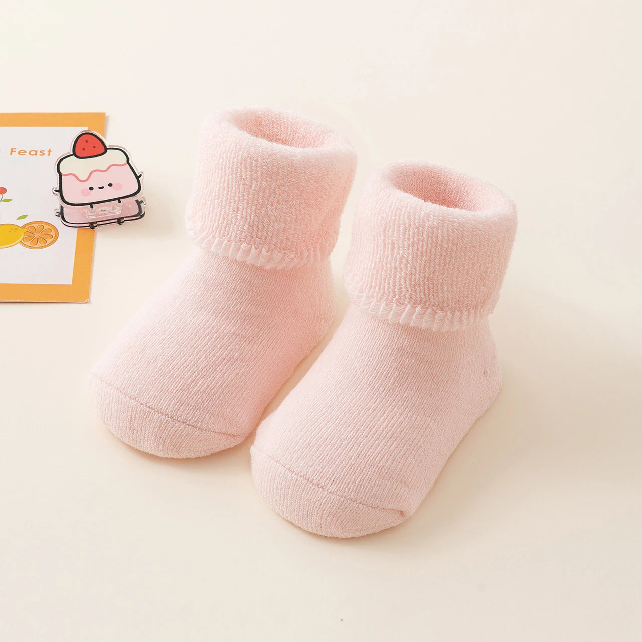 Pair of pink baby socks on a light beige background
