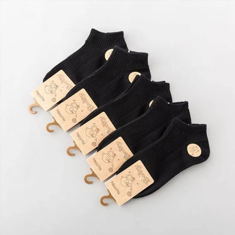 Set of black ankle socks with brand tags on a light gray background