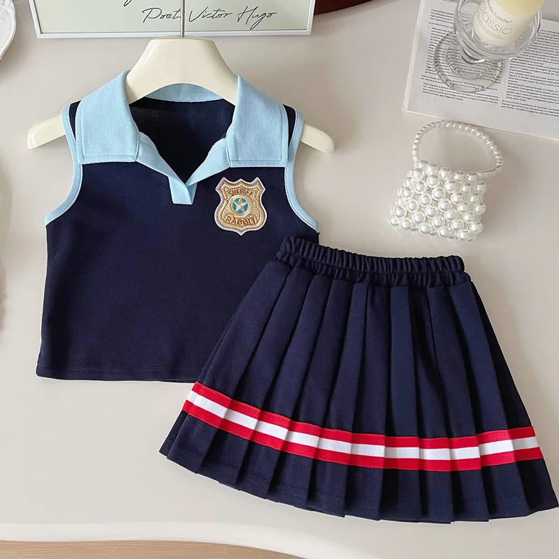 Children's navy blue outfit with light blue collar and red and white striped skirt on a neutral background.
