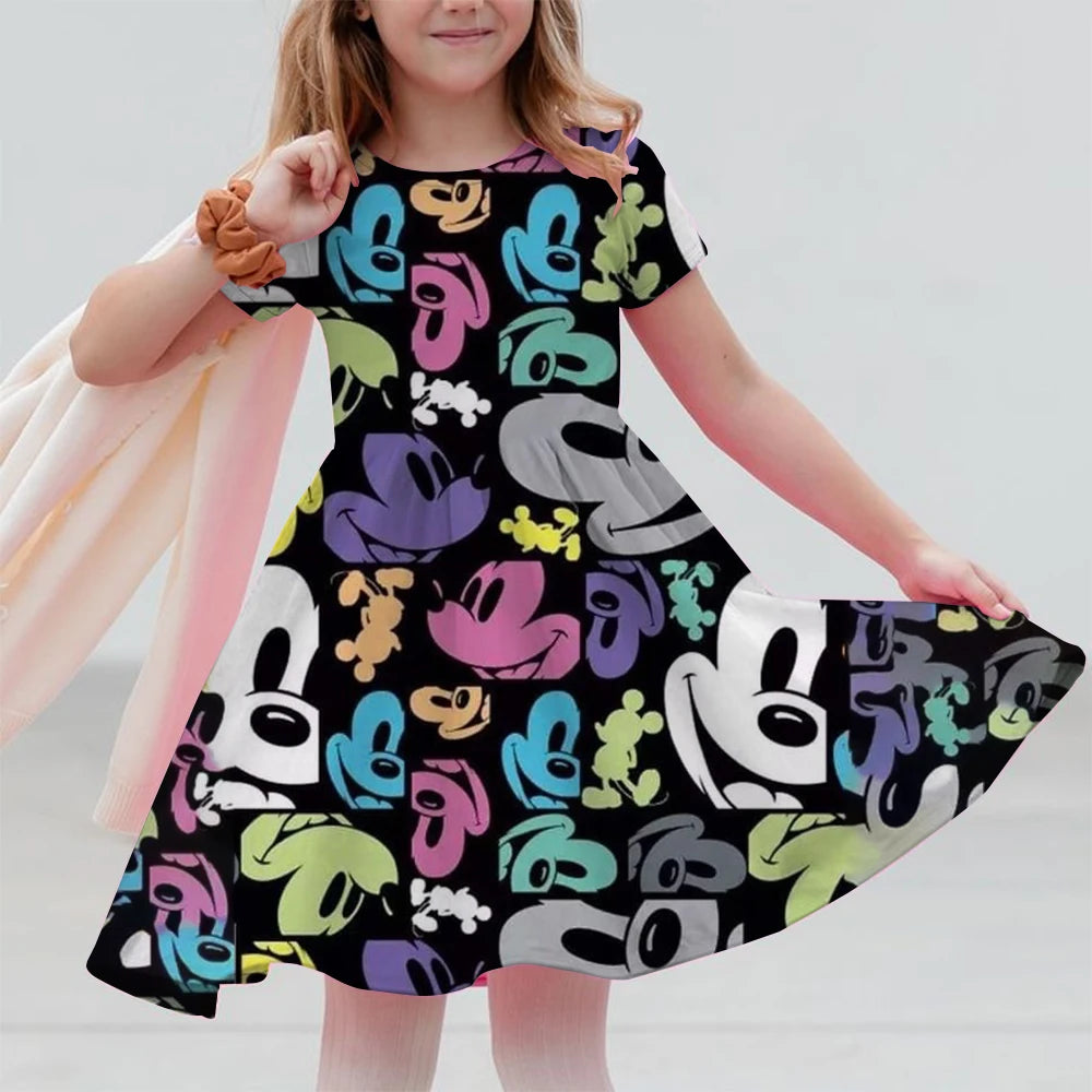 Child wearing a colorful dress with cartoon character pattern on a plain background