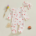 Baby romper with heart patterns, headband, and toys on a light background