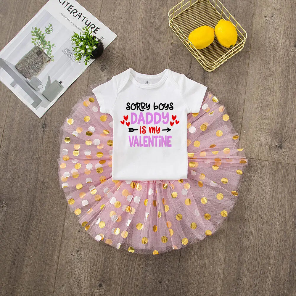 White t-shirt with text and pink tutu skirt on a wooden surface