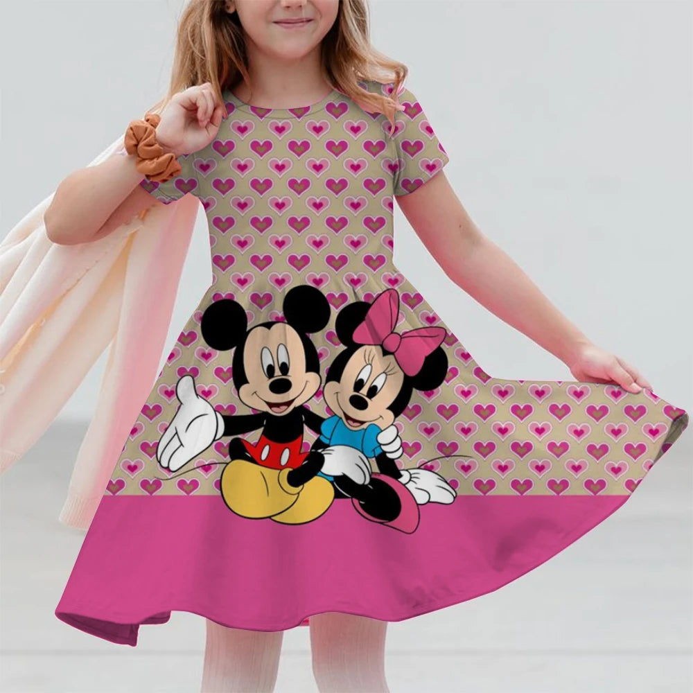 Child wearing a dress with Mickey and Minnie Mouse design on a plain background