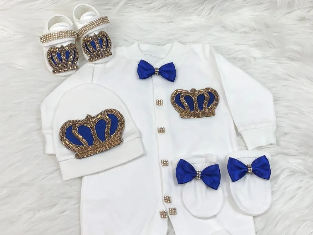 Baby outfit with white shirt, pants, and hat featuring blue bow ties and crowns on a white background.