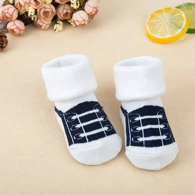 Pair of white baby socks with navy blue patterns on a beige background
