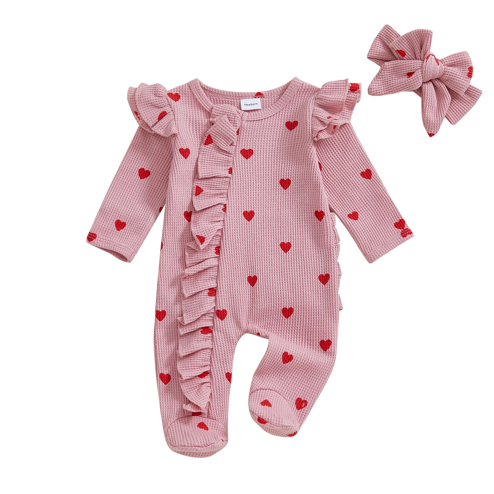 Pink baby romper with heart patterns and matching headband on a white background
