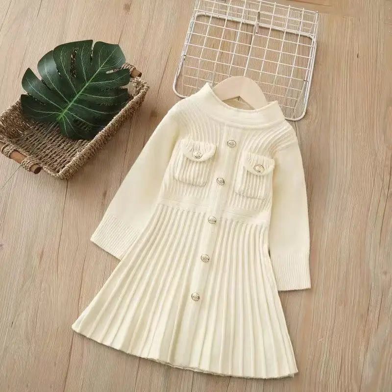 White ribbed knit dress on a wooden surface with a basket and leaf.