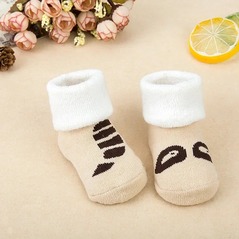 Pair of baby socks with paw print design on a beige background