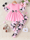 Pink dress with cat pattern and matching leggings on a textured surface with accessories.