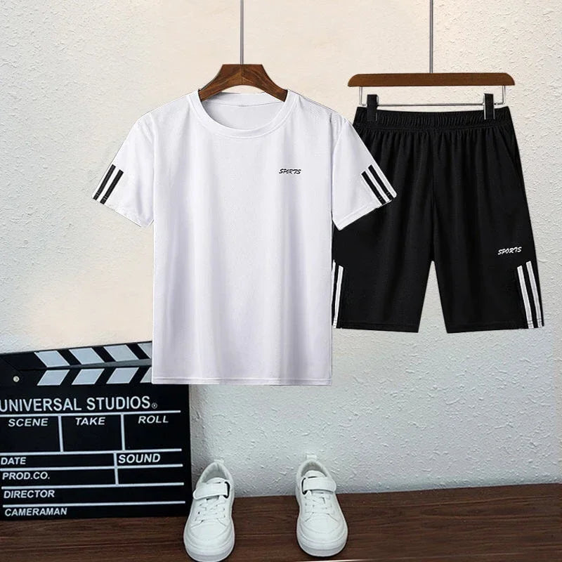 White t-shirt and black shorts with stripes on hangers, white sneakers on a wooden floor, and a clapperboard in the background.