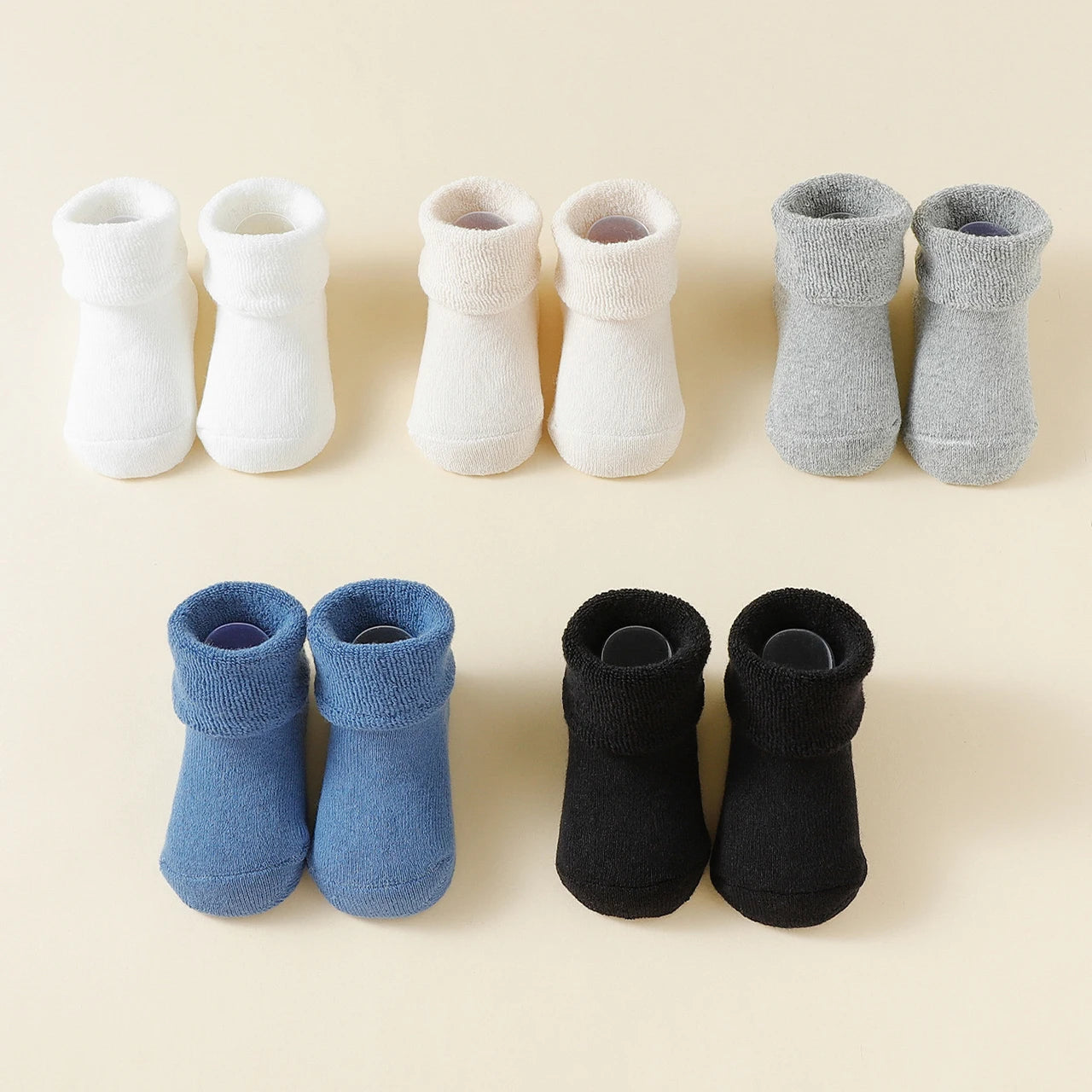 Set of baby socks in white, gray, blue, and black on a beige background