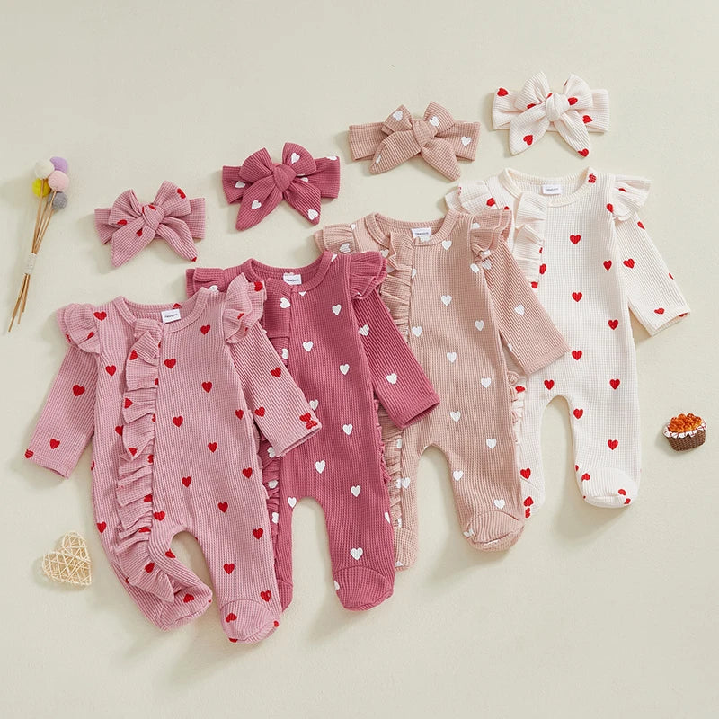 Set of baby rompers with heart patterns and matching headbands on a light background