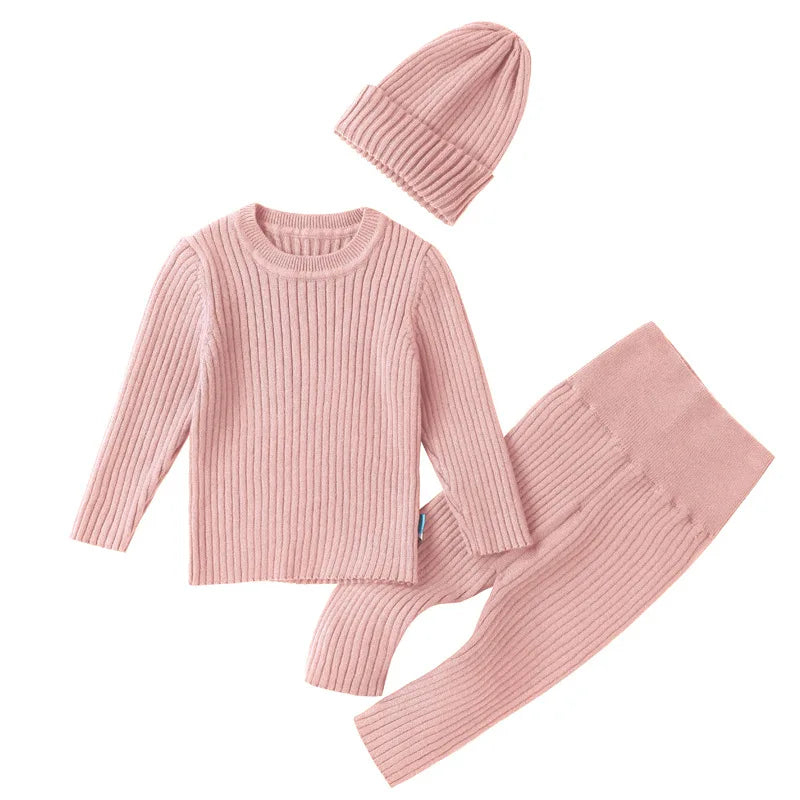 Pink knit sweater, pants, and beanie set on a white background