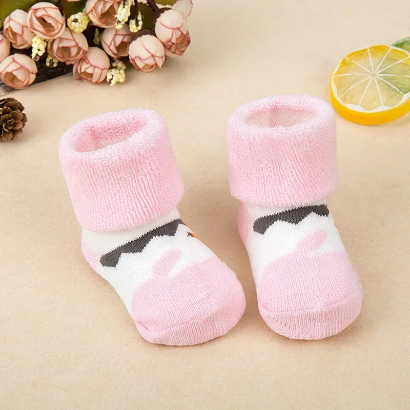 Pair of pink baby socks with paw print design on a beige background
