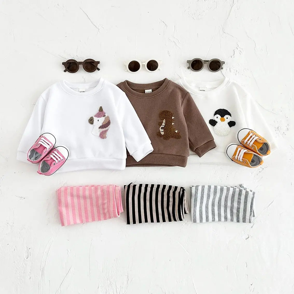 Children's clothing set with two sweatshirts, shorts, and shoes on a white background