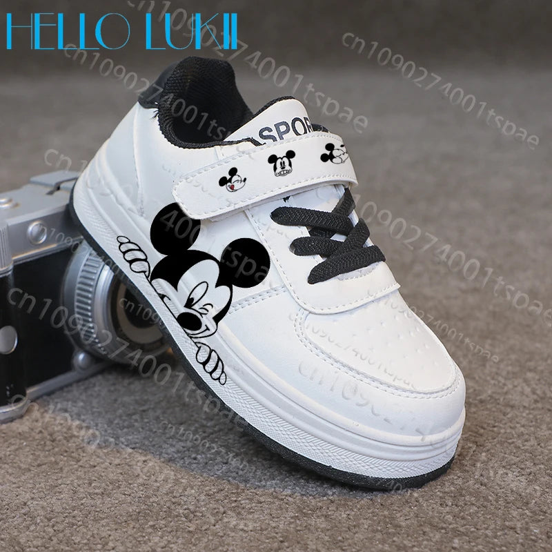 White children's shoe with black Mickey Mouse design on a textured surface