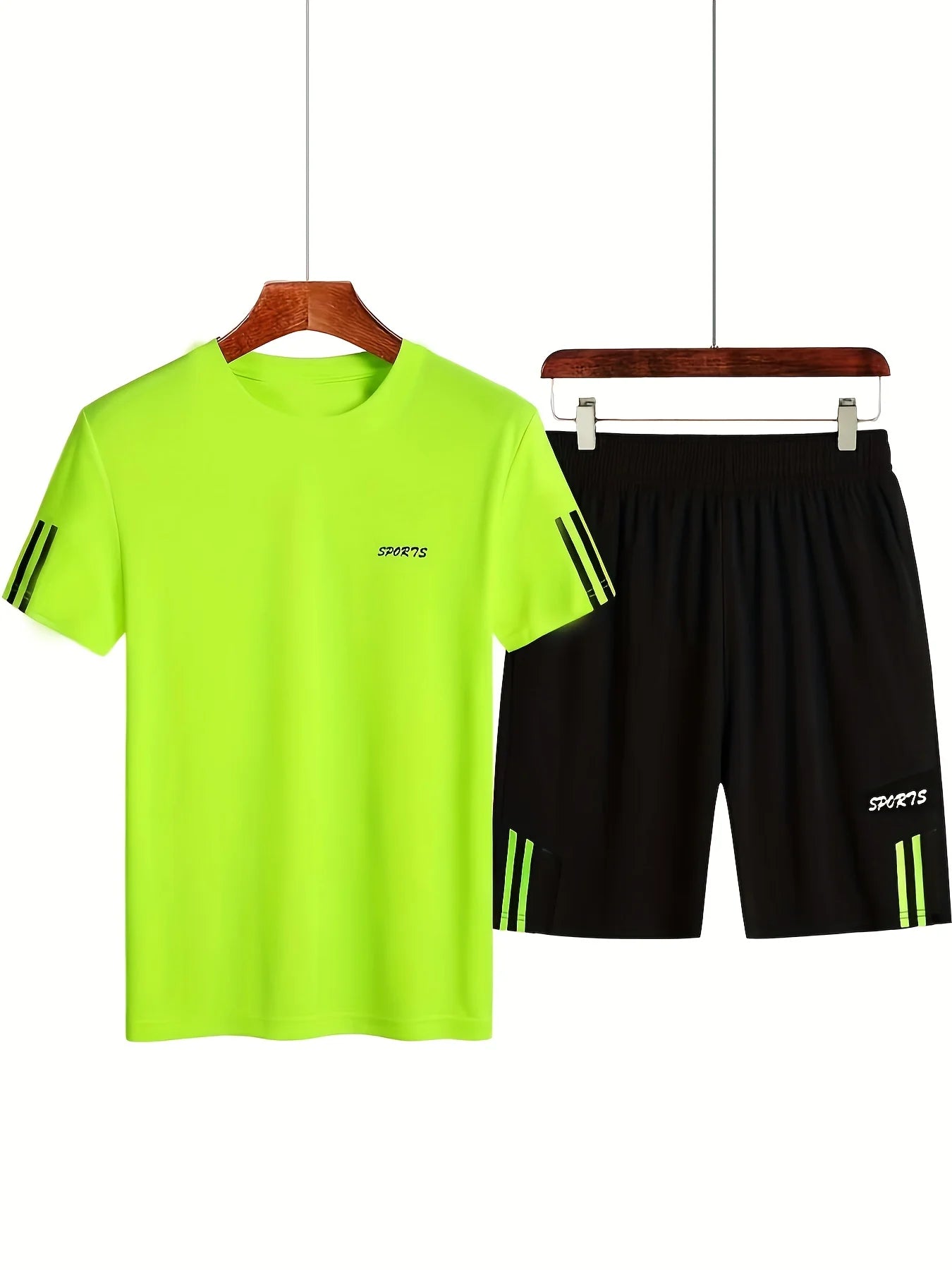 Green t-shirt and black shorts set on hangers against a white background