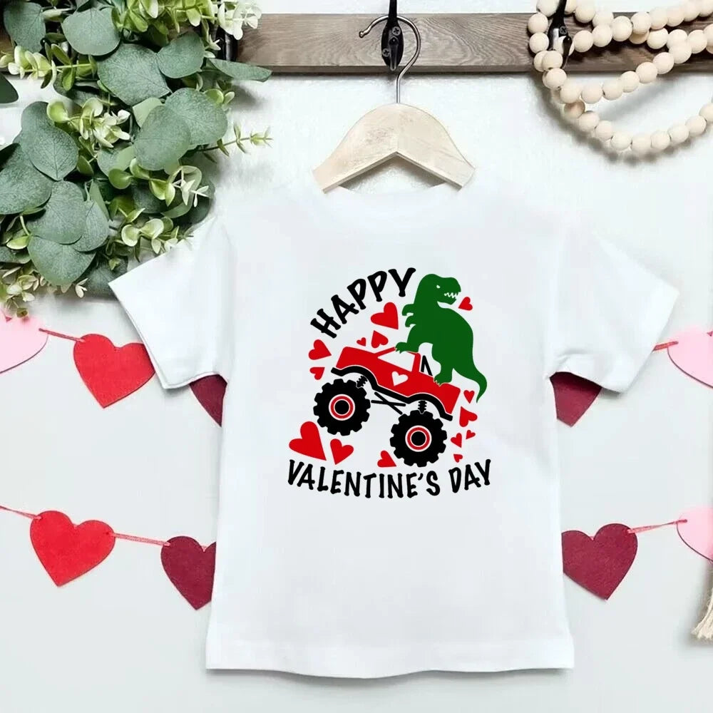 White t-shirt with Valentine's Day design featuring a green dinosaur and red hearts on a hanger.