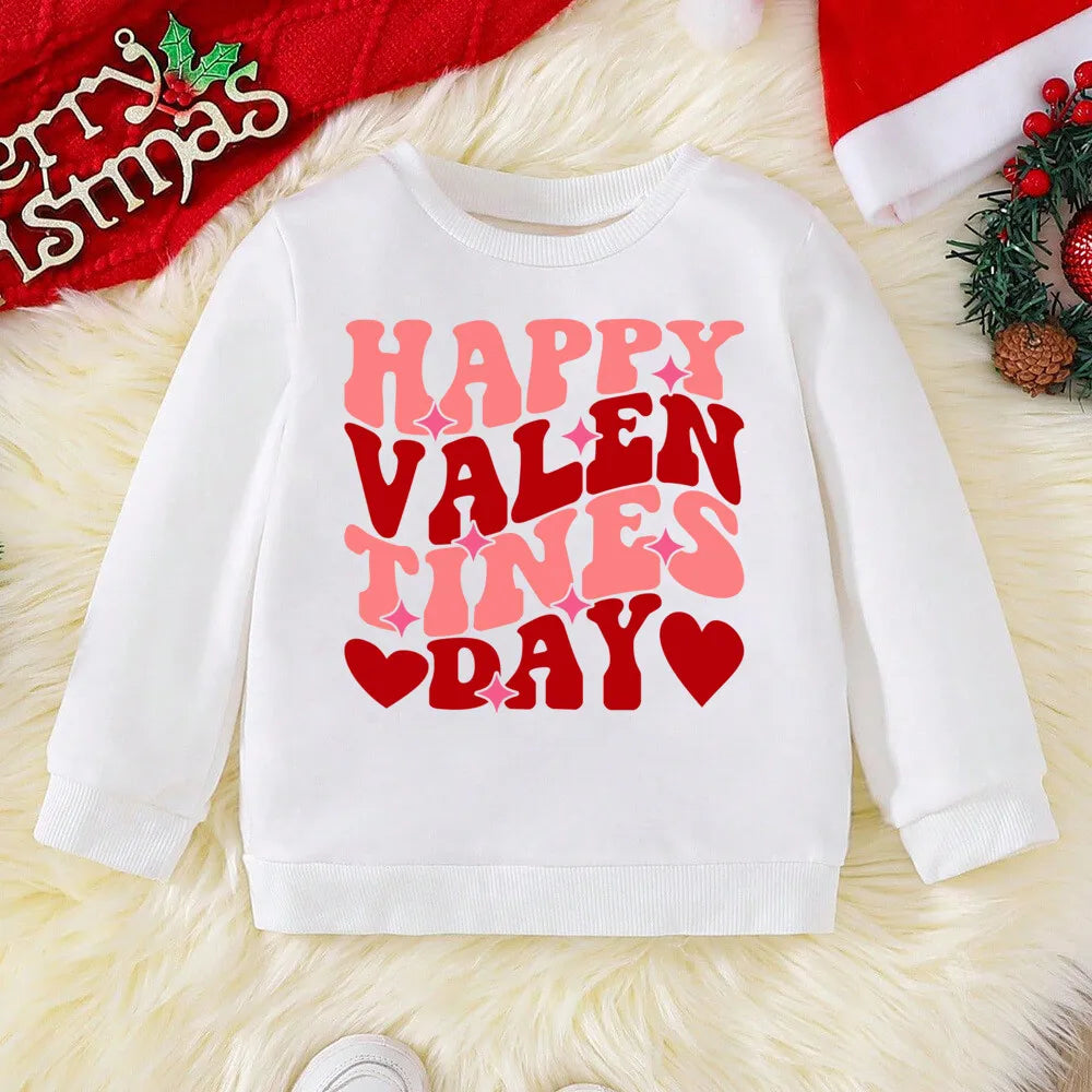 White sweatshirt with 'Happy Valentine's Day' text on a textured surface with Christmas decorations.