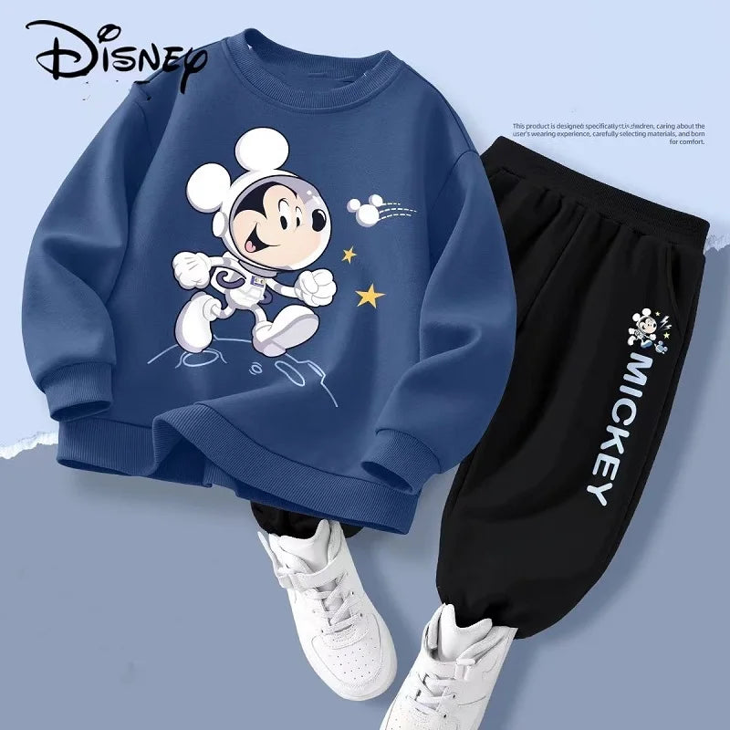 Children's outfit with blue sweatshirt and black pants featuring a cartoon character, white sneakers on a light blue background.