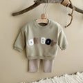 Children's outfit with 'OH BOY' text on a wooden hanger against a beige wall.