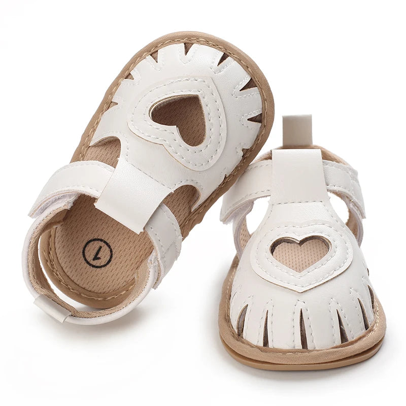 White baby sandals with heart designs on a white background