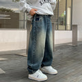Person wearing a gray sweatshirt, blue jeans, and white sneakers standing on a wooden deck.